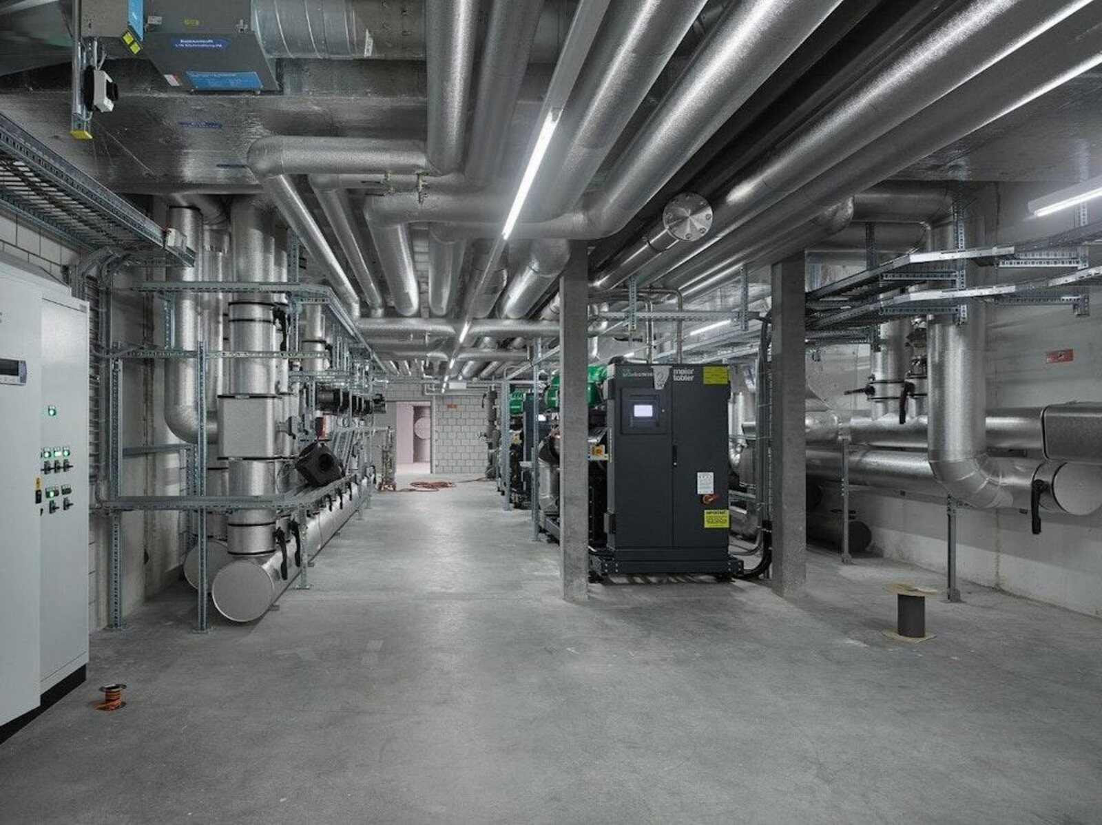 Centrale thermique d’un campus universitaire à Ecublens : réseaux de tuyauterie calorifugée, gaines galvanisées et armoires techniques.